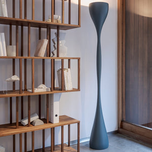 Lampada da terra Jazz di Vibia posizionata vicino alla libreria un soggiorno moderno, che proietta una luce indiretta sul soffitto.