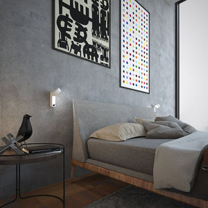 Applique da lettura Toggle Martinelli Luce installata in verticale accanto a un letto.