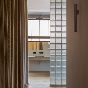 Applique Koko Uno in finitura bronzo installata in un corridoio dal design contemporaneo