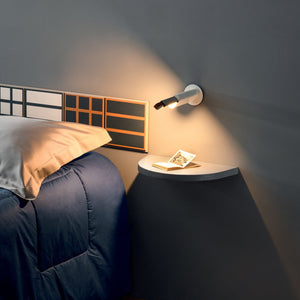 Applique interattiva Metrica di Martinelli Luce installata sulla parete di una camera da letto, con la luce parzialmente estratta per lettura.