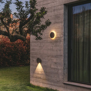 Applique orientabile Dots Outdoor che proietta un fascio di luce d'accento sulla facciata in cemento di una villa.