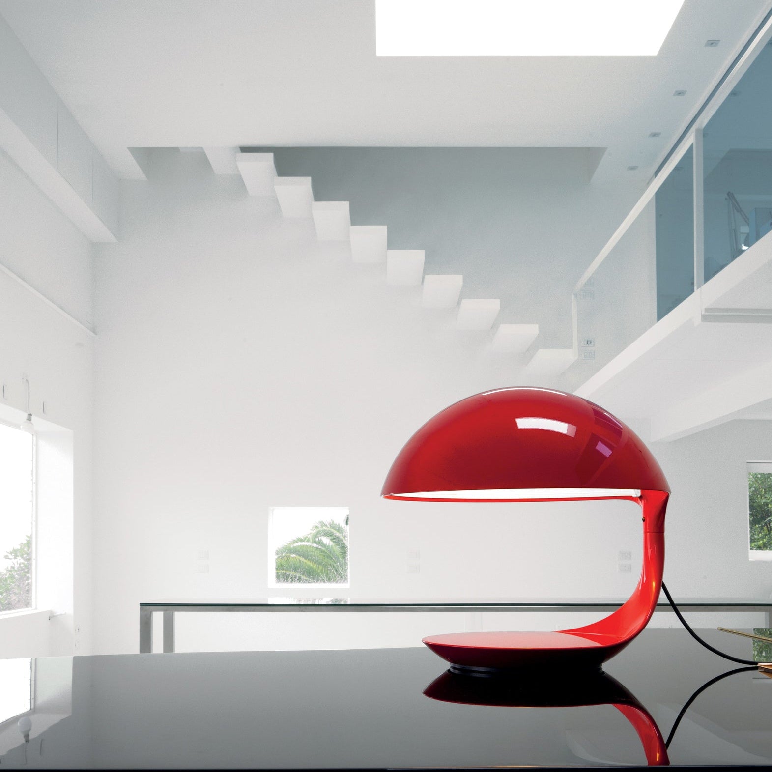 Lampada da tavolo Cobra di Martinelli Luce, colore rosso, su una scrivania di un ufficio dal design minimalista