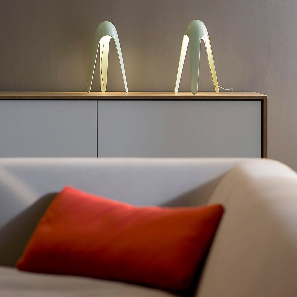 Lampada Cyborg di Martinelli Luce posizionata su una consolle in un salotto moderno.
