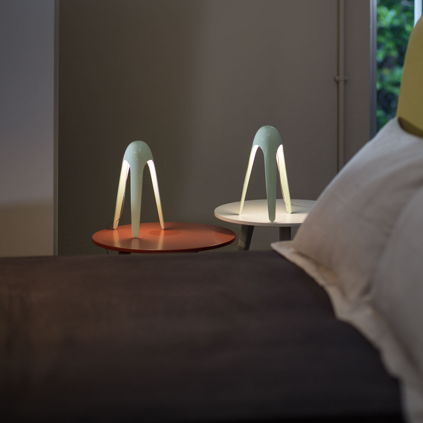 Lampada da tavolo di design Cyborg accesa su un comodino in una camera da letto.