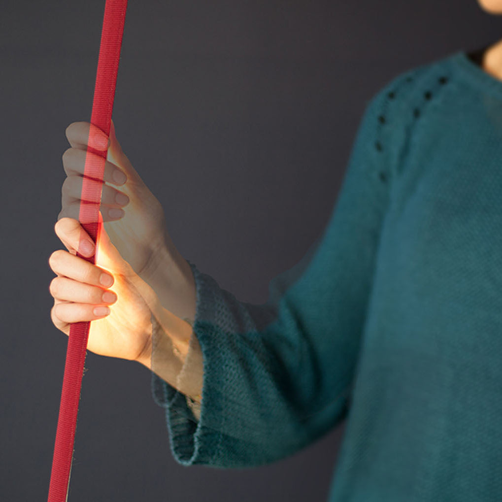 Dettaglio di una mano che sfiora l'elastica accesa di martinelli luce.
