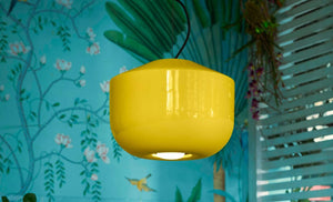 Dettaglio del lampadario giallo Belotta firmato Ferroluce in un salotto con carta da parati floreale