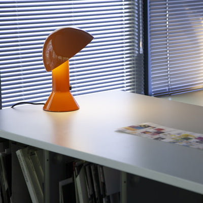  Lampada di design Elmetto arancione posizionata su una scrivania in un ufficio moderno.