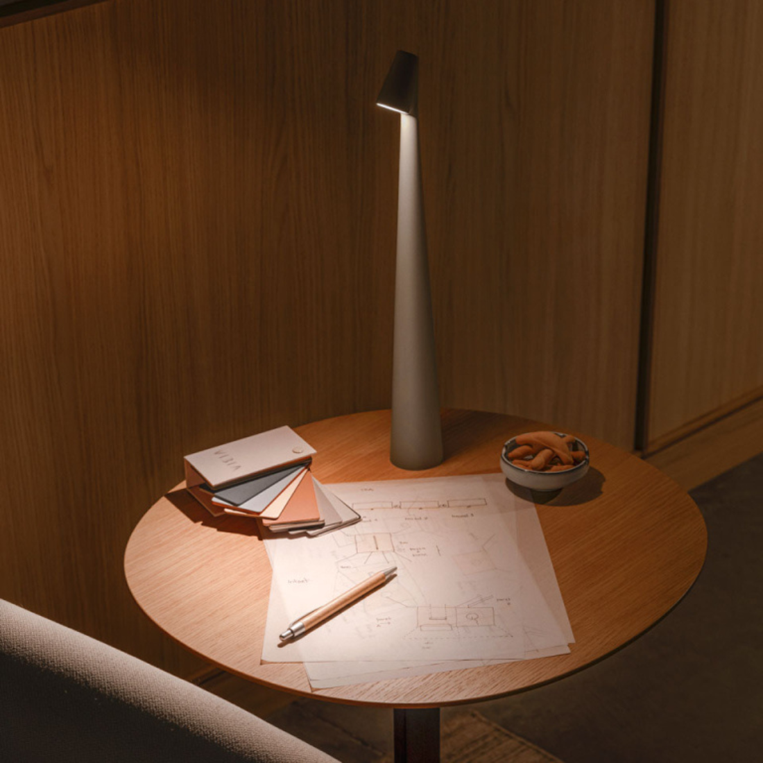 Lampada portatile Africa di Vibia posizionata sopra un tavolino in legno accanto a un divano.