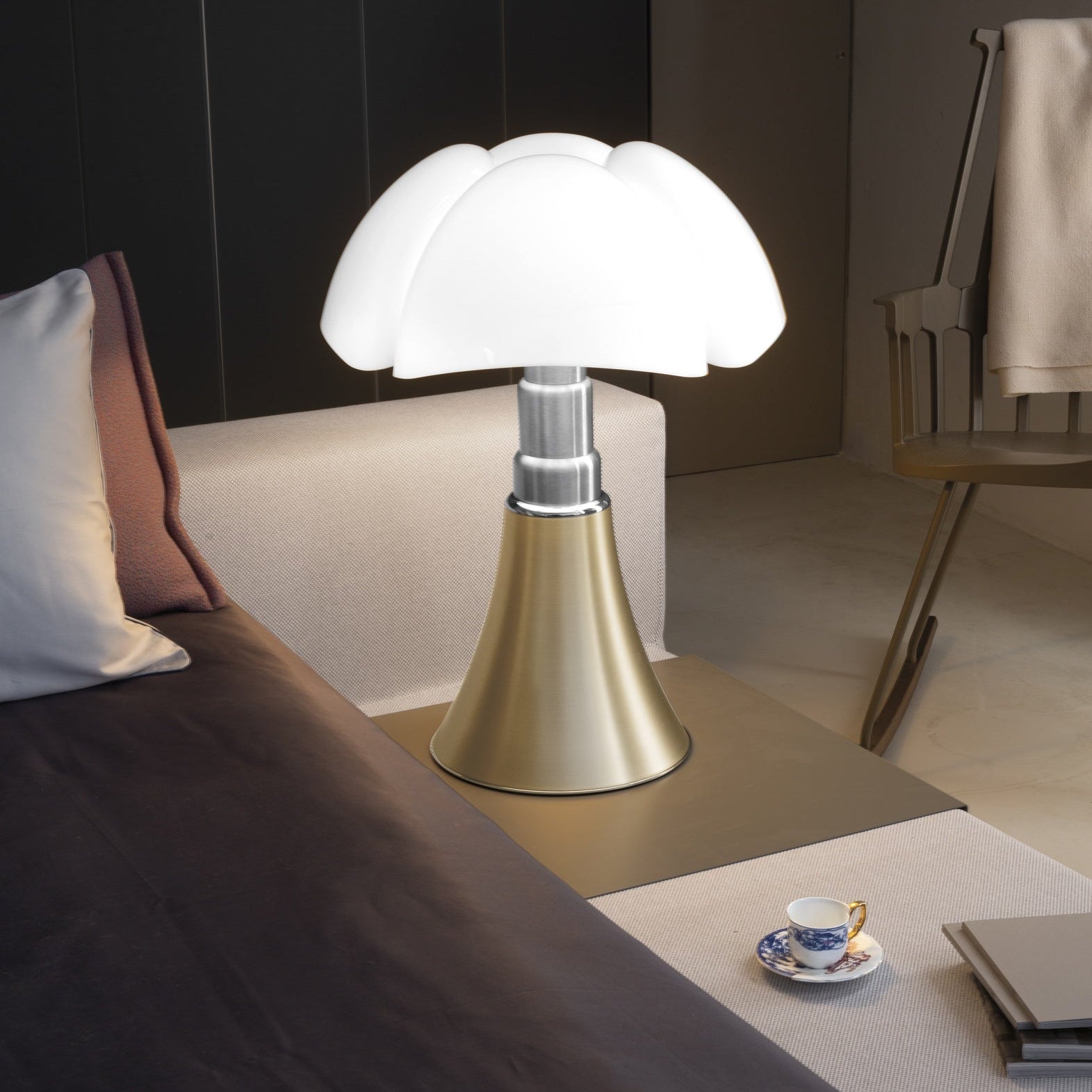 Lampada Pipistrello di Gae Aulenti versione bronzo,posizionata su un comodino.
