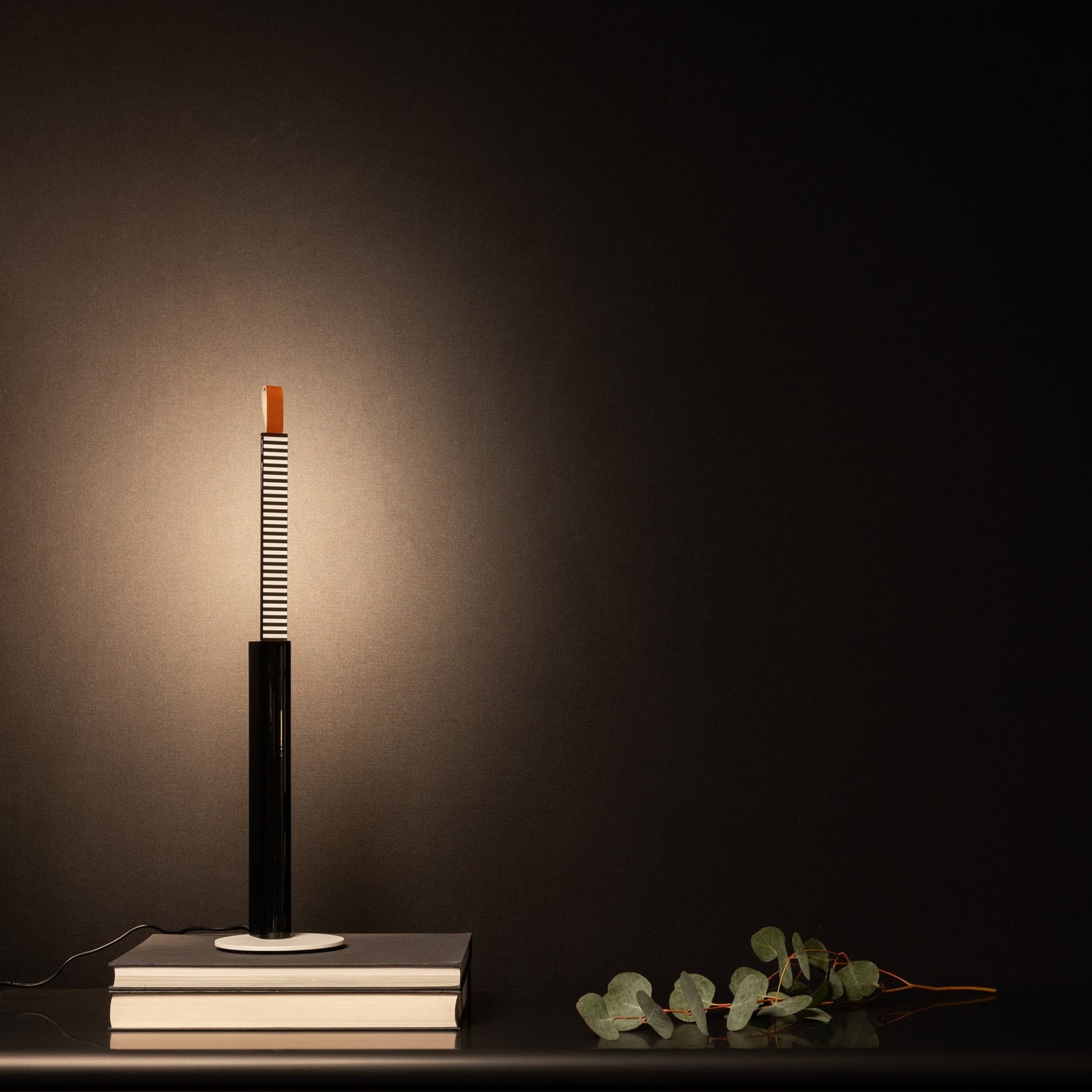 Lampada da tavolo Metrica posizionata su una credenza, con la sorgente luminosa estratta.