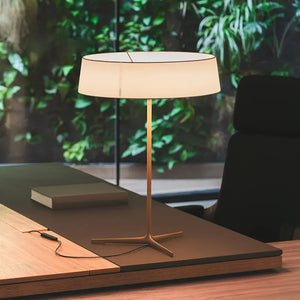 Lampada da tavolo DAMA di Vibia posizionata in un ufficio moderno, che crea un'atmosfera calda e rilassante con la sua luce diffusa.