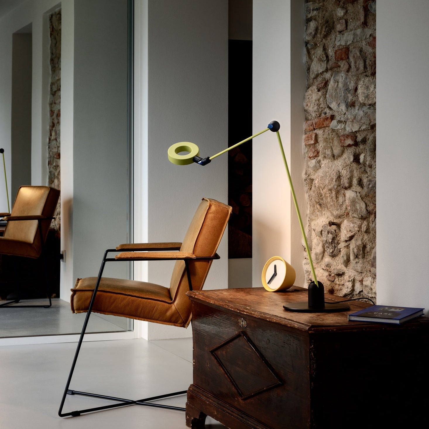 Lampada da tavolo L'Amica usata come luce da lettura su un comodino, con il fascio di luce diretto su una poltrona.