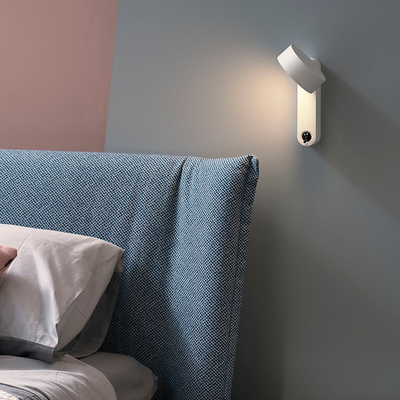 Lampada da parete Toggle di Martinelli Luce in posizione verticale sopra una testata del letto.