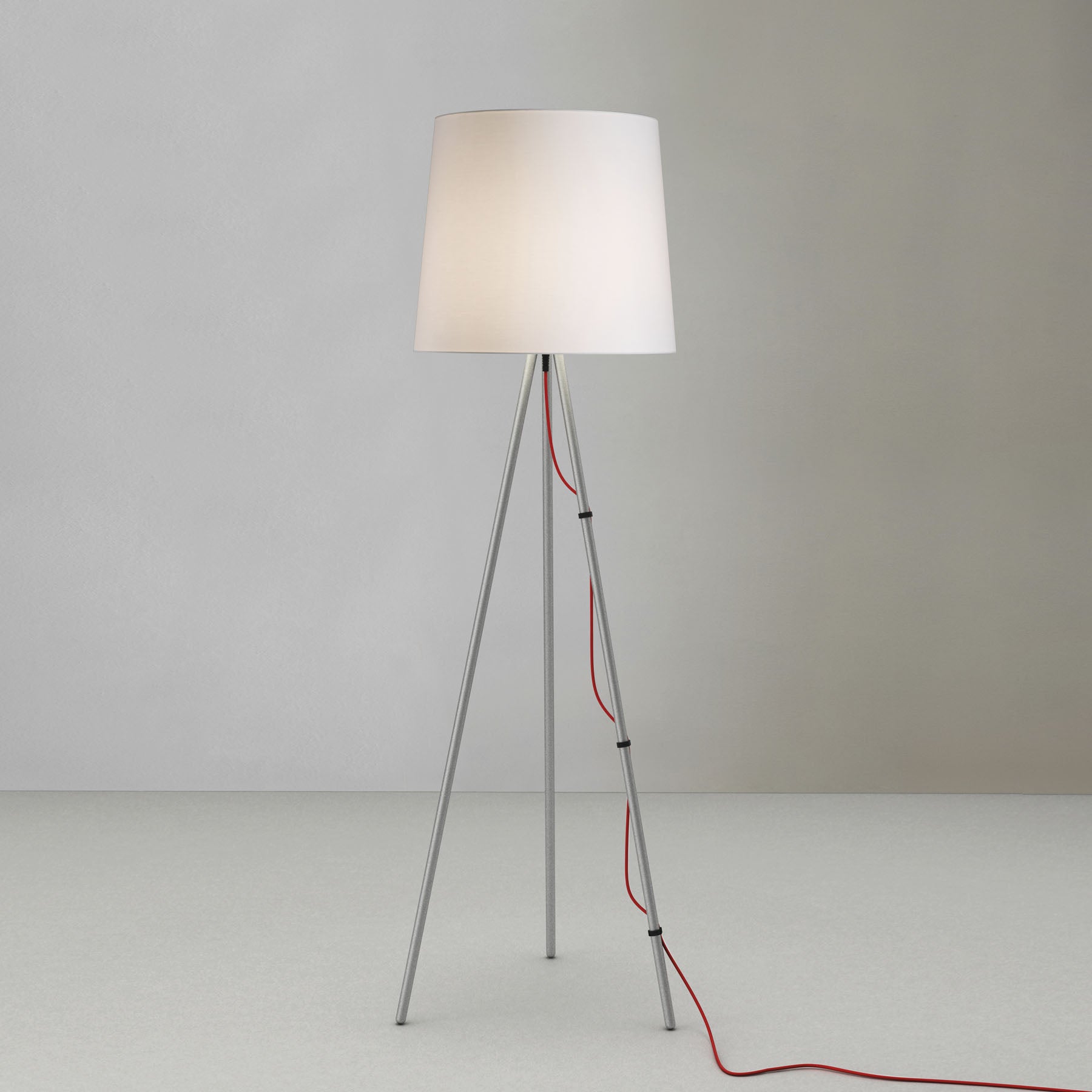 Lampada da terra con diffusore bianco e filo rosso su sfondo bianco.