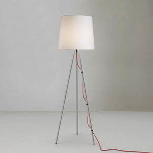Lampada da terra con diffusore bianco e filo rosso su sfondo bianco.