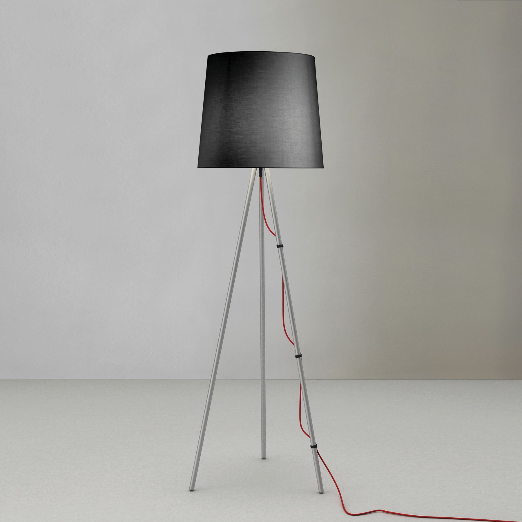 Lampada da terra con diffusore nero e e treppiede in alluminio di martinelli luce su sfondo neutro.