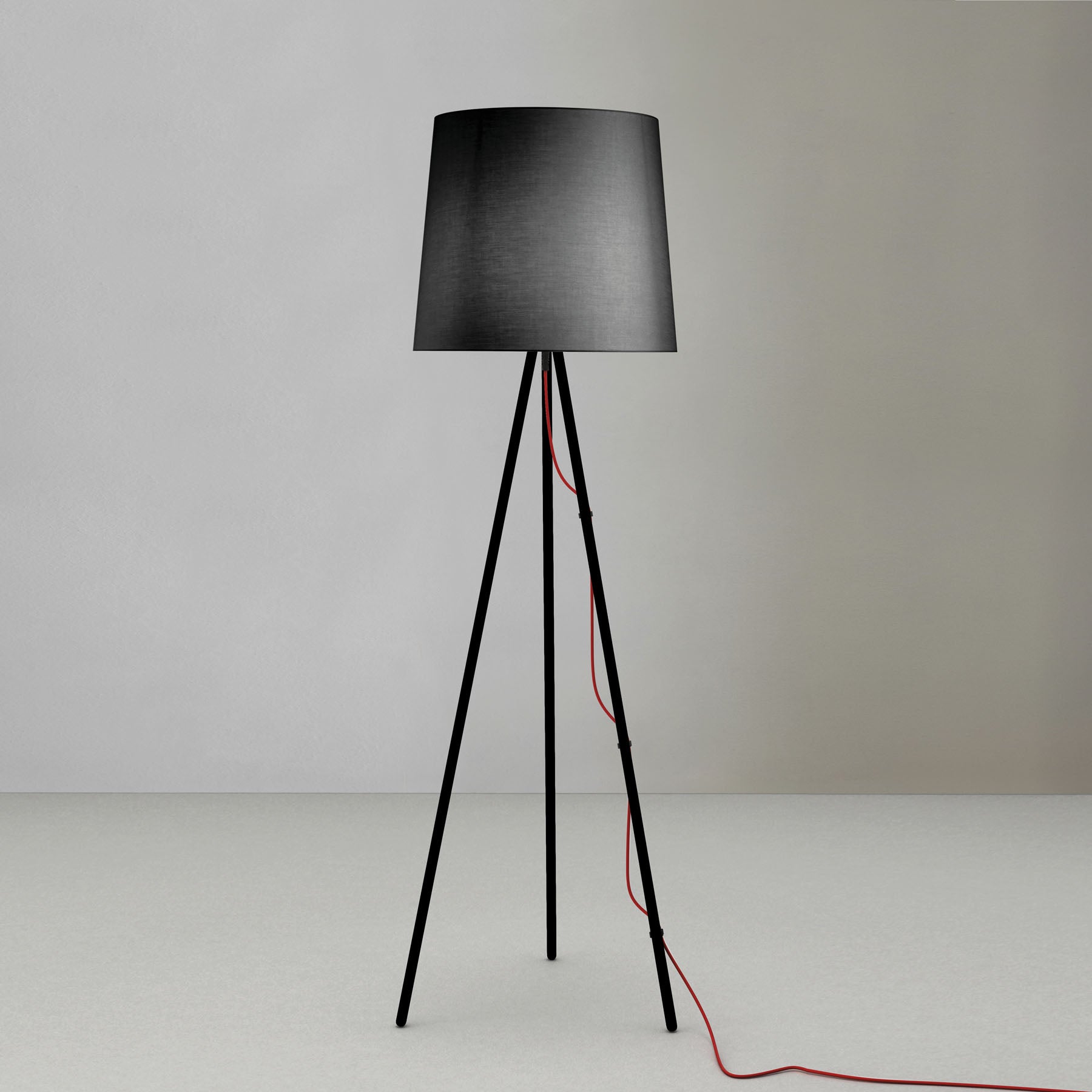 Lampada da terra con diffusore nero e e treppiede in alluminio nero di martinelli luce su sfondo neutro.