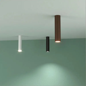 Serie di plafoniere Koko Uno in finitura bianca, nera e bronzo installate per illuminare un lungo corridoio minimale