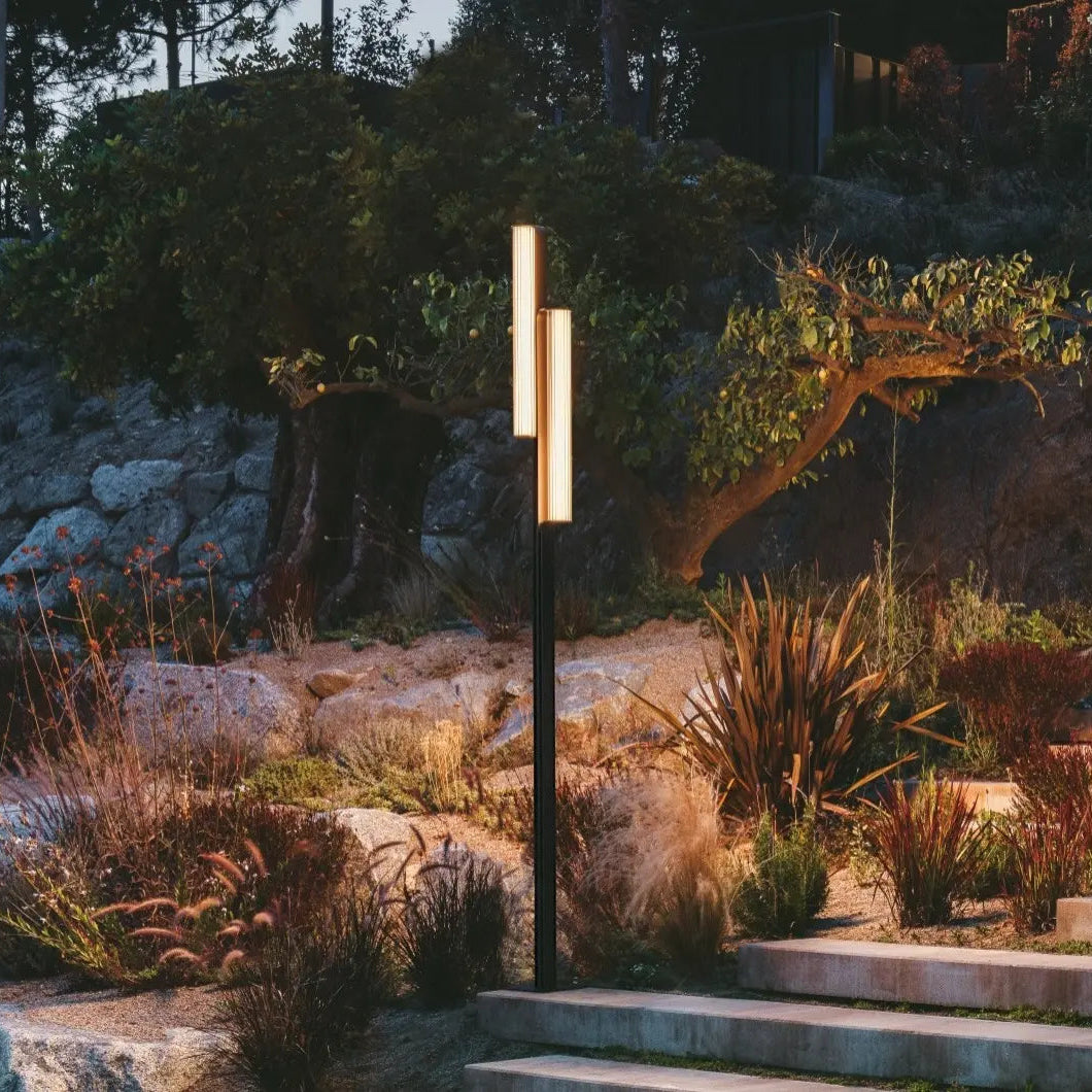 Paletto alto Class Vibia installato in giardino moderno di sera con luce calda 2700K che illumina percorso in pietra naturale