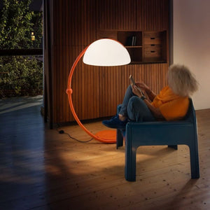 Iconica lampada Serpente 60 che illumina un angolo lettura con il suo colore arancione.