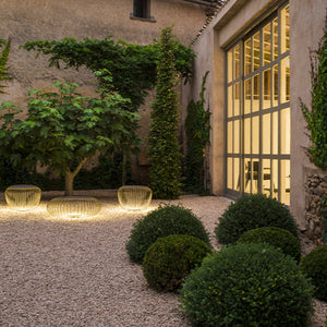 Gruppo di sgabelli luminosi Meridiano usati come sedute in una zona lounge in un giardino durante una serata estiva.
