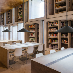 Sistema Plusminus con nastri tesi e sospensioni che illuminano le postazione di lettura in una biblioteca