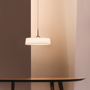 Sospensione DAMA di Vibia installata sopra un tavolo da pranzo in legno, che crea un'atmosfera intima.