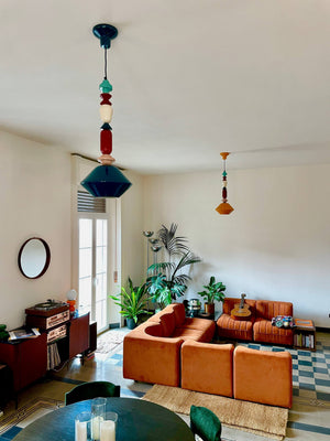 Sospensione lunga Lariat C2511 installata in un living con soffitti molto alti.
