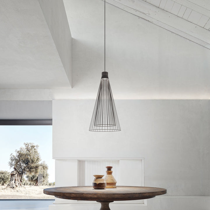 Lampada a sospensione Ikonika di Karman installata sopra un tavolo da pranzo rustico. 