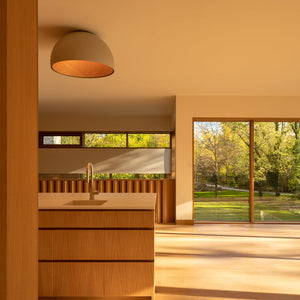 Isola cucina in legno illuminata con la plafoniera a cupola Duo di VIBIA